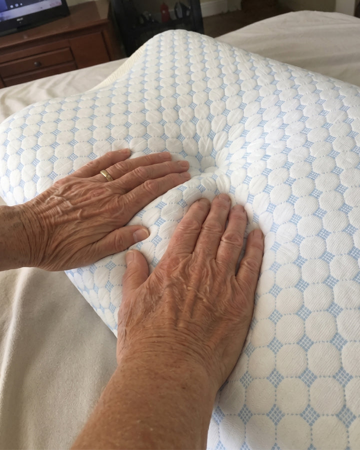 Hands pressing into the centre gap of the Serenium Relief Pillow